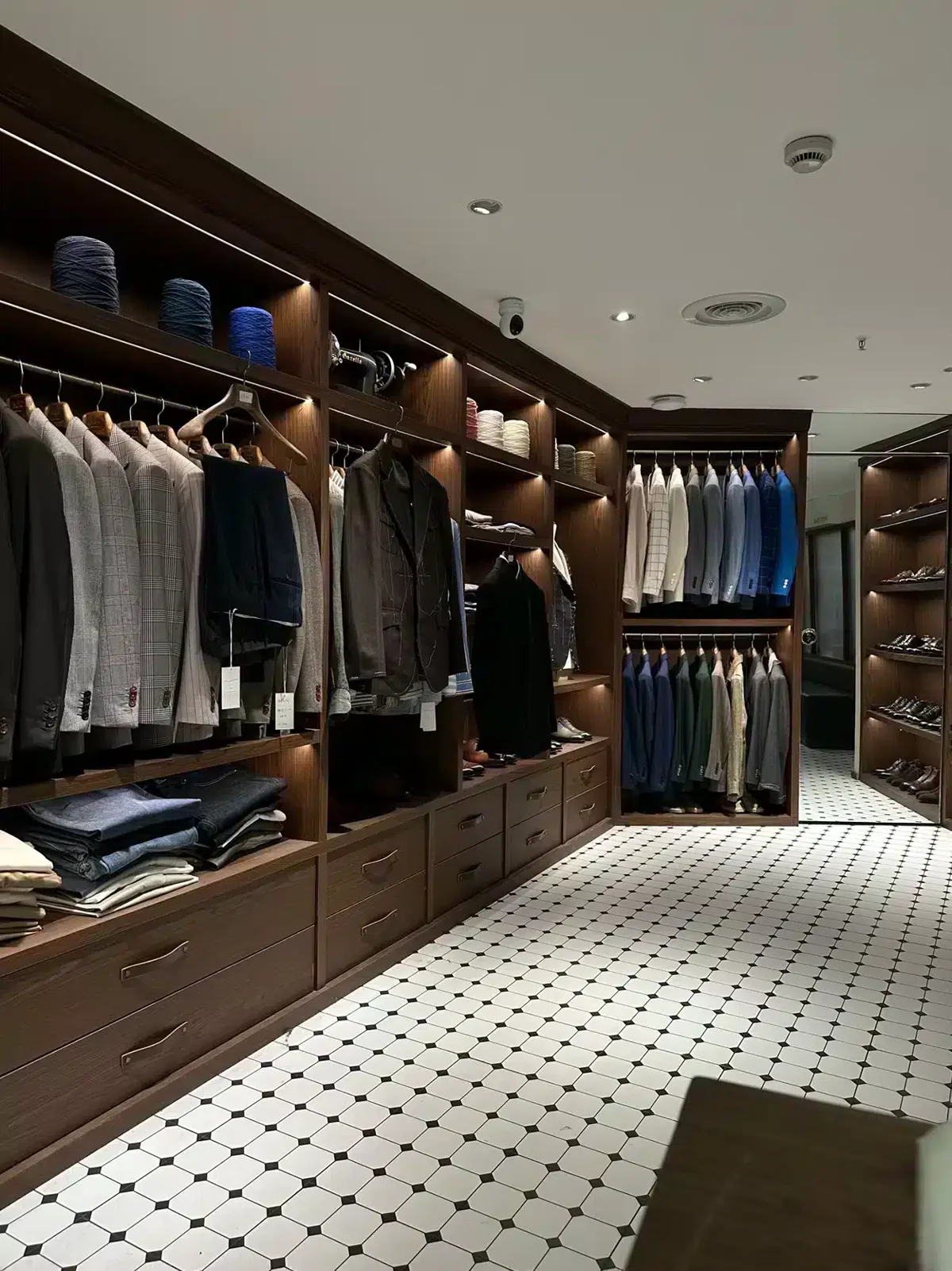 Menswear showroom with dark wood shelving and wooden suit hangers